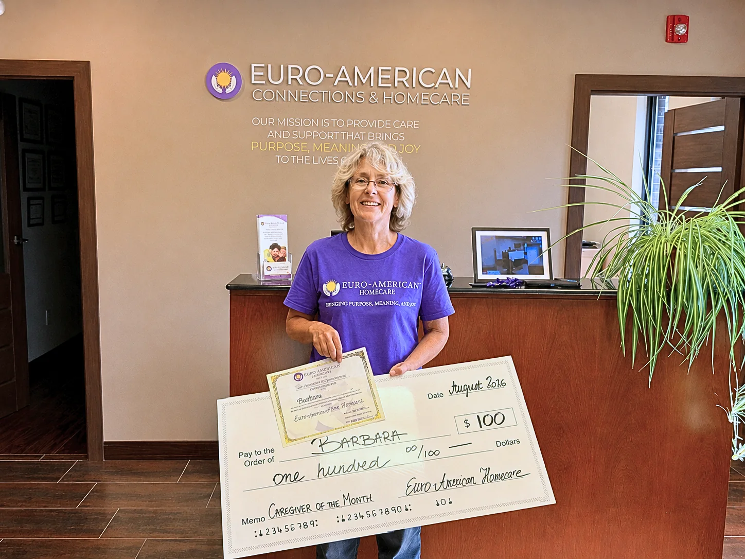 Caregiver Barbara smiling with her certificate and Caregiver of the Month award