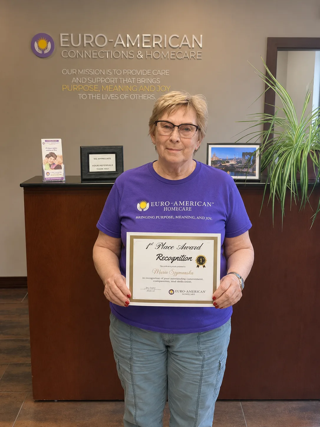 Caregiver Maria holding her first-place recognition certificate in the Euro-American Homecare office