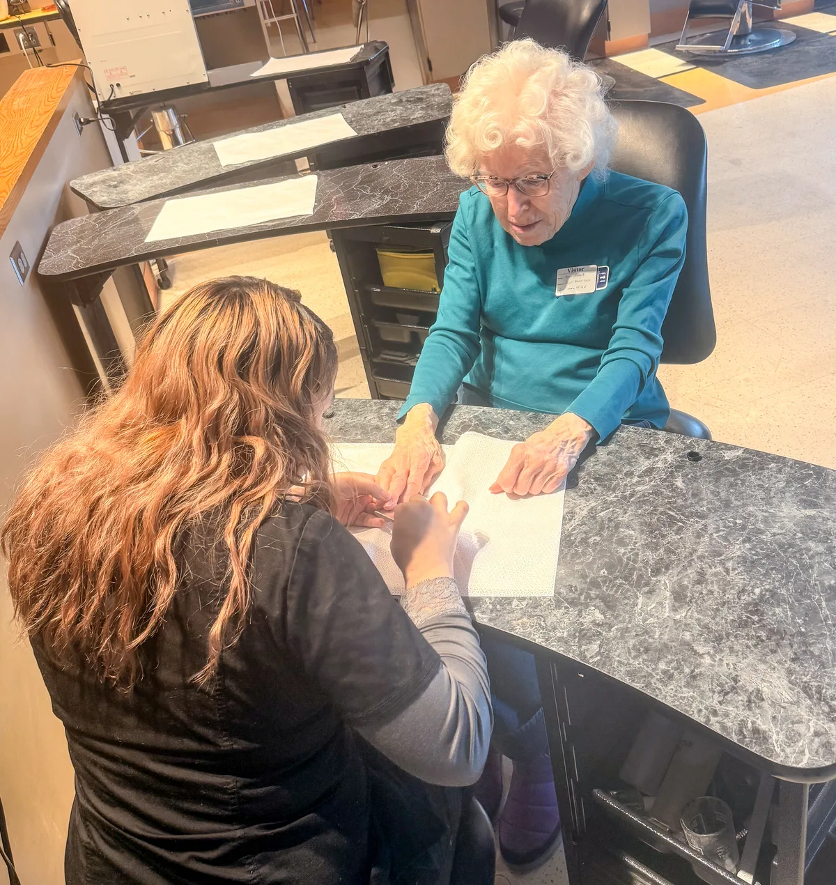A cosmetology student giving a client a manicure at the Spa Day