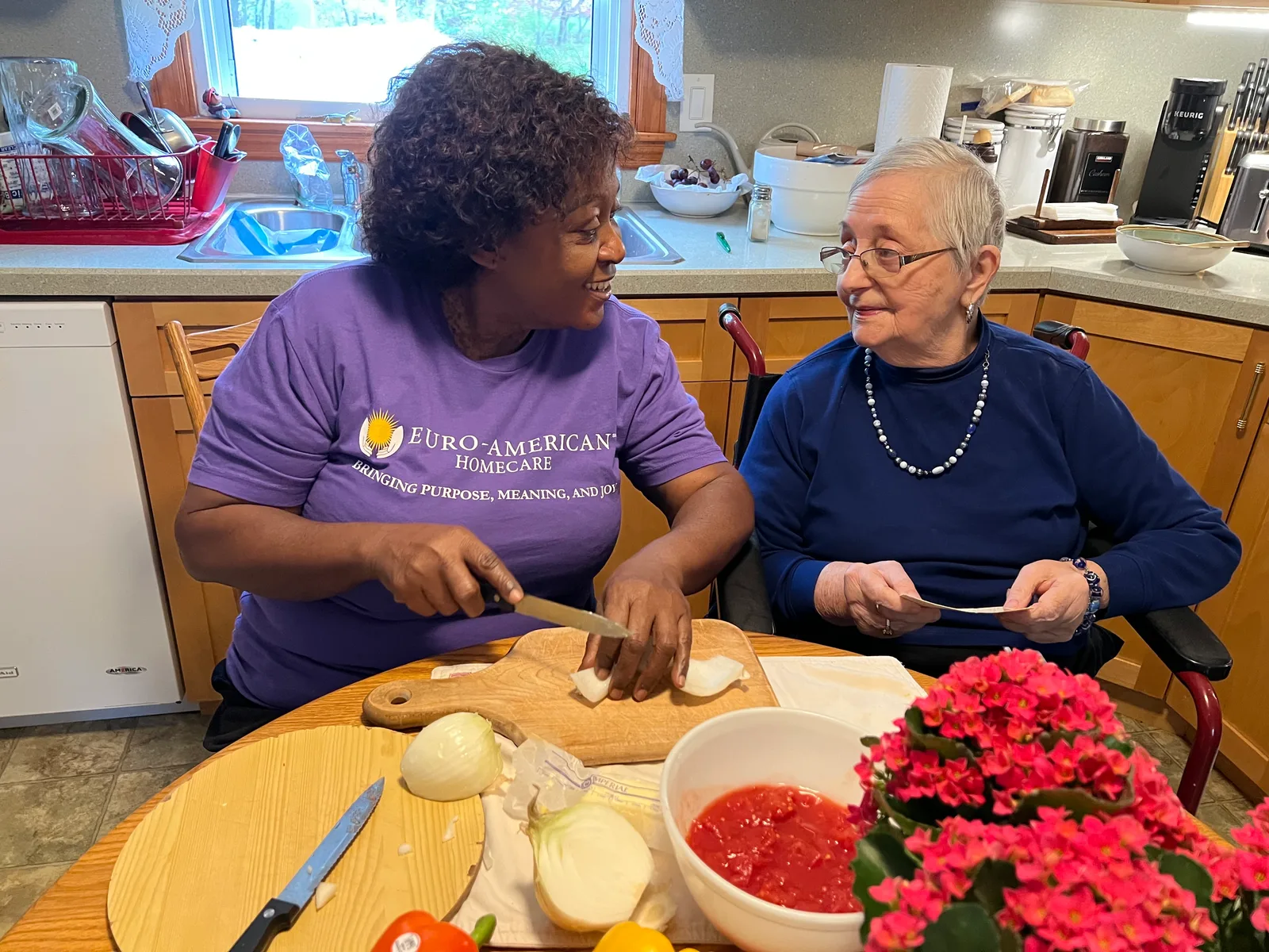 A caregiver and client preparing vegetables together in the kitchen