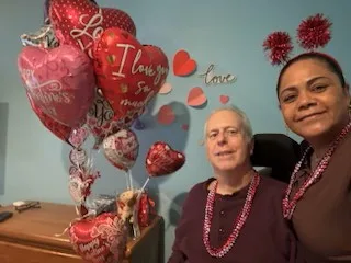 A client and caregiver celebrating together with Valentine's Day balloons