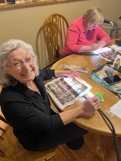 Two clients smiling while working on a photo craft at the table