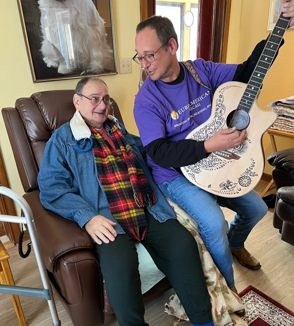 Caregiver Frank playing guitar and singing with his client