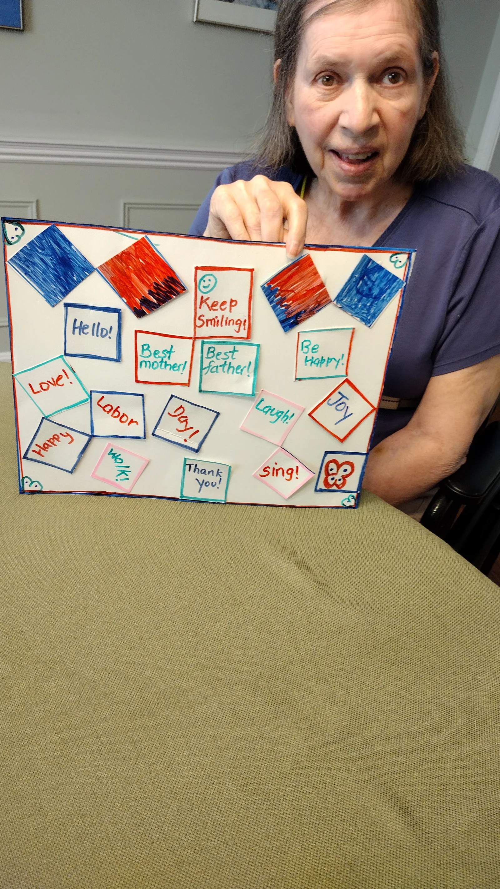 A client holding up a colorful poster of cheerful notes like “Keep Smiling!” and “Joy”