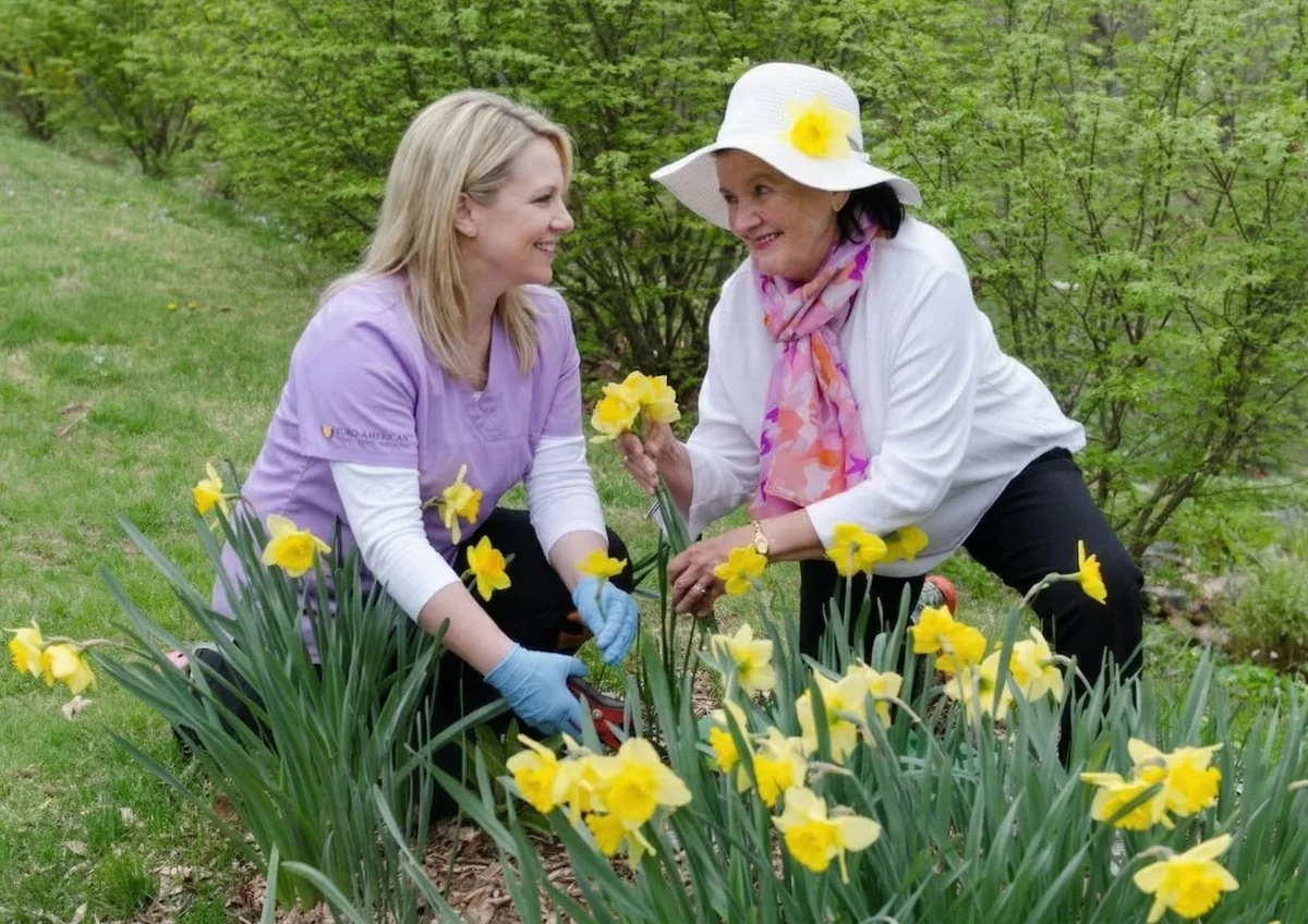 Caregiver and senior tending daffodils together in the garden